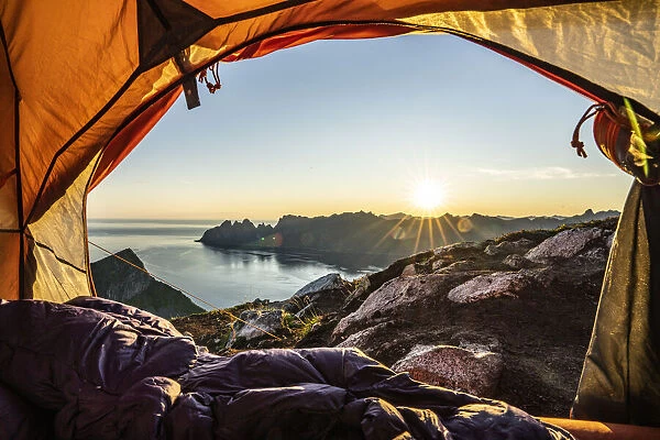 Warm lights of sunrise view from the inside of hikers tent, Senja island