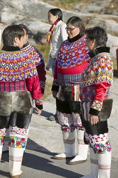 Inuit women wearing traditional Greenlandic national costume or Kalaallisuut in Ilulissat on Greenland. The costume consists of seal skin boots(Unnaat) bead necklaces (Nuilaqutit) and seal skin trousers