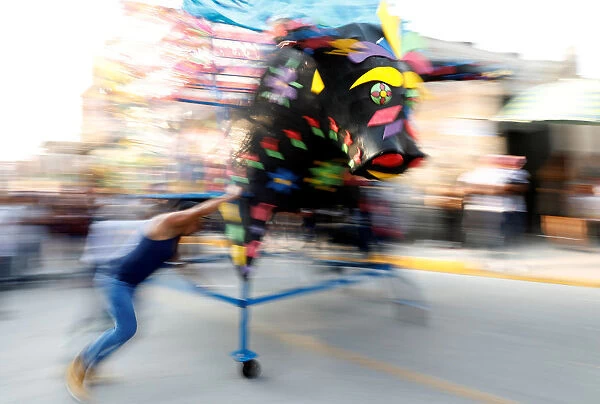 Man spins a traditional bull figure surrounded by fireworks, known as El Torito