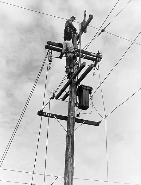 ELECTRIFICATION, 1938. Workmen installing electricity on the top of utility poles