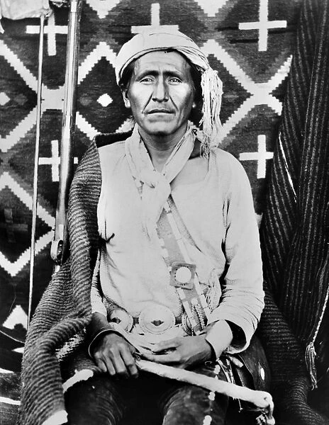 A Navajo shaman posed in front of a woven blanket. Photographed by John K. Hillers, c1880