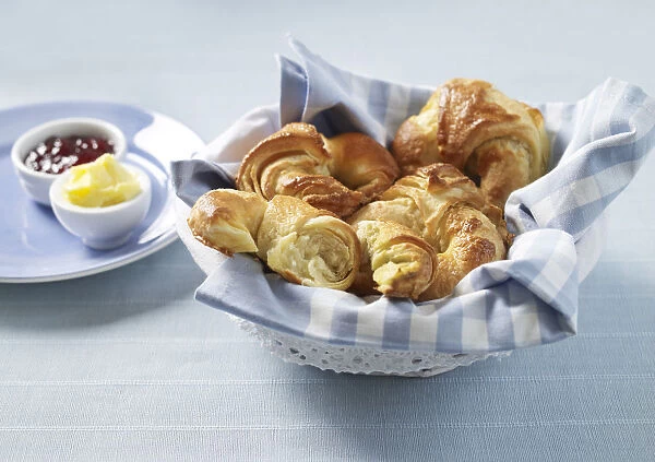 Basket of croissants, butter and jam