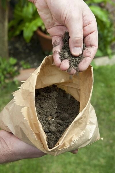 Holding soil in hand above paper bag