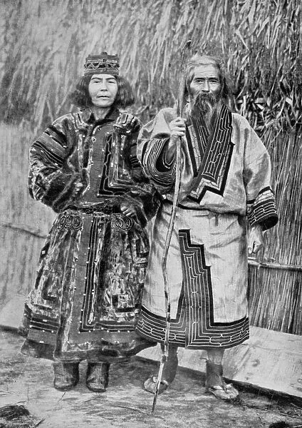 Ainu Couple outside the traditional Ainu home of a reed thatched hut