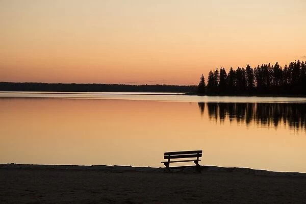 A Bench Silhouetted At Sunset Near The Lake