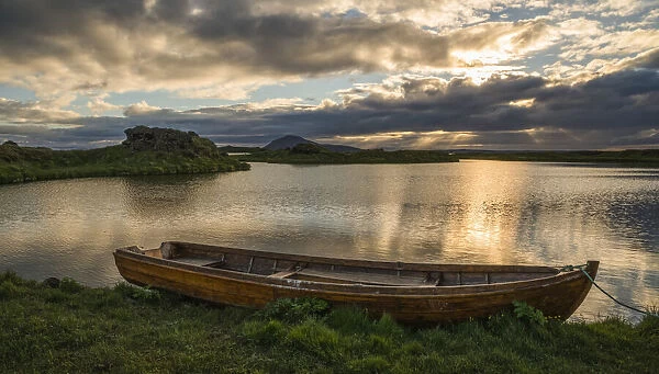 A boat lies in a placid Lake Myvatn, North Iceland at sunset; Iceland