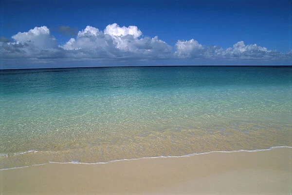 Calm Shoreline Water With Many Different Shades Of Blue, Clouds Above Horizon