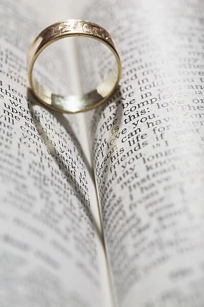 Close up of a gold ring with the shadow of an heart on book about love; Calgary Alberta Canada