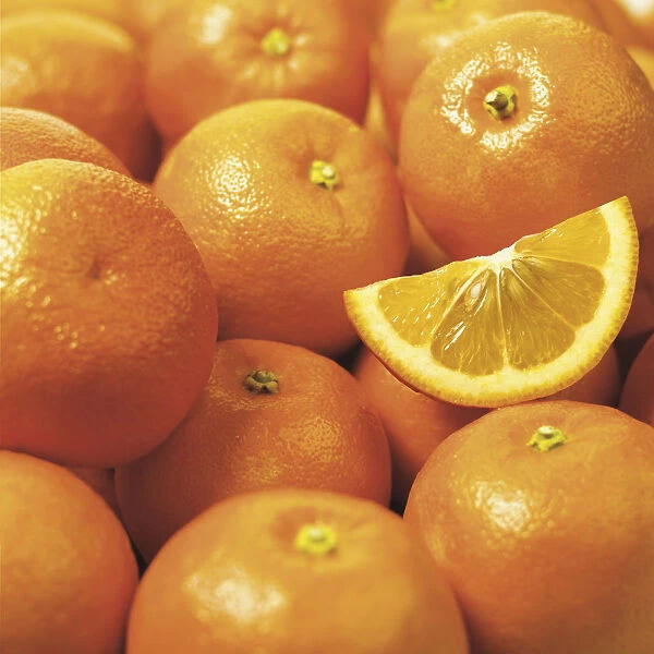 Close-Up Of A Bunch Of Oranges And One Slice