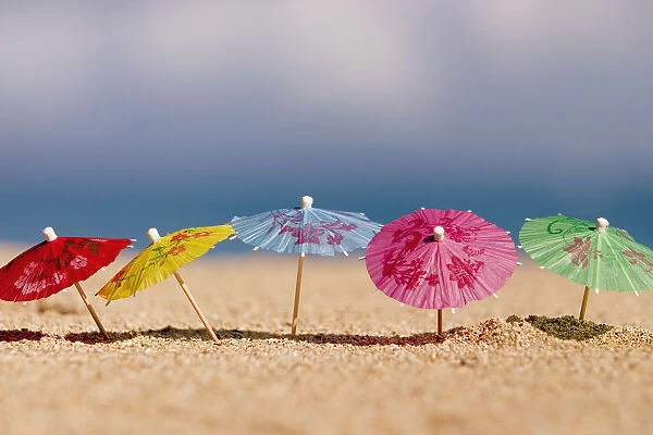 Close-Up Of Cocktail Umbrellas In The Sand