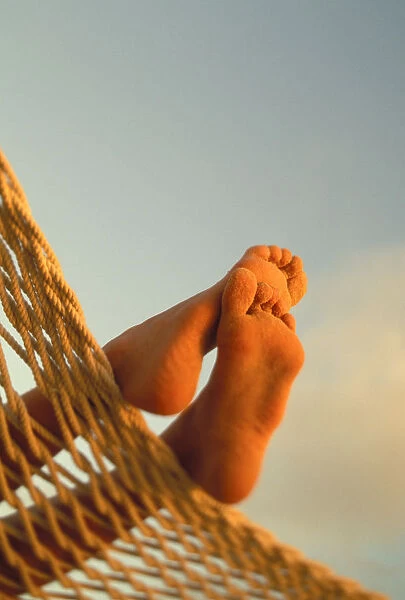 Close-Up Of Bottom Womans Feet Crossed, Hammock With Golden Afternoon Light, Sand