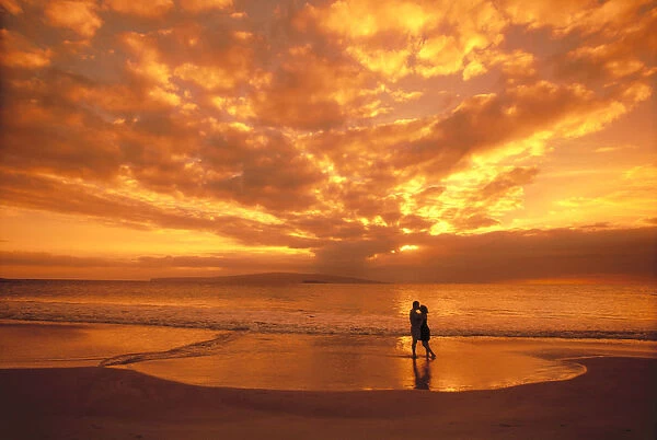 Couple Silhouetted On The Beach During Sunset, Fiery Orange Sky, Clouds
