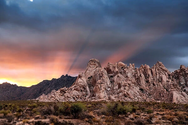 Crepuscular rays at sunset behind rock formations in the Mojave Desert, Kelso, California, USA
