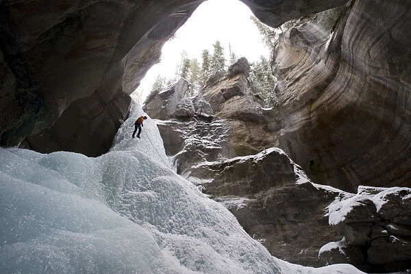 Female Ice Climber Rappels Into The Head Of Maligne Canyon In Jasper National Park, Alberta, Canada