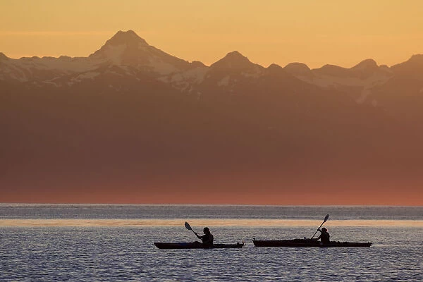 Two Female Sea Kayakers Enjoy A Warm Summer Evening While Paddling In Favorite Passage, Alaska, Near Eagle Beach State Recreation Area, Juneau. Chilkat Mountains Beyond
