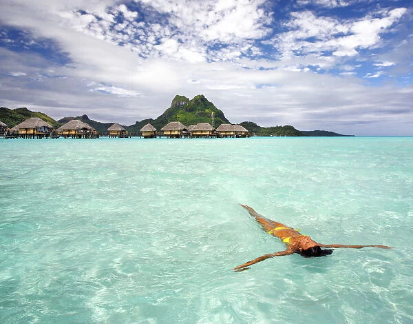 French Polynesia, Tahiti, Bora Bora, Woman Floating In Water Near Resort