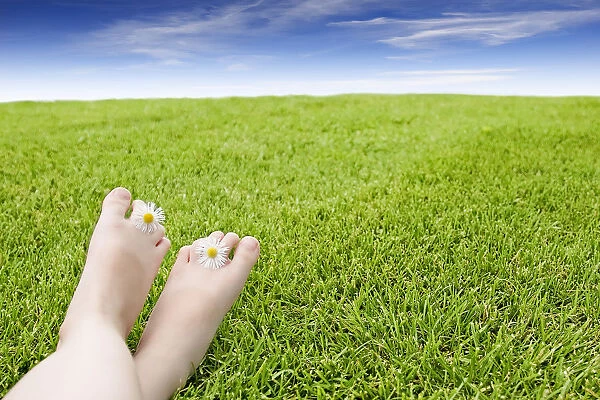 Girls Feet On Grass With Flowers Between Her Toes