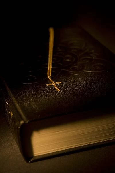 Gold Cross Pendant Resting On A Book
