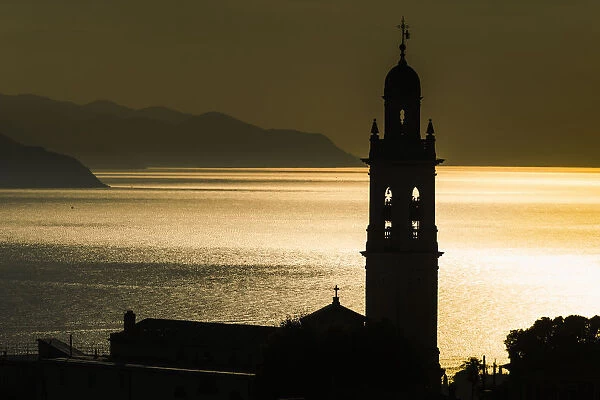Golden Sunlight Reflected On Water At Dusk With Tower Of Church; San Lorenzo Della Costa, Liguria, Italy