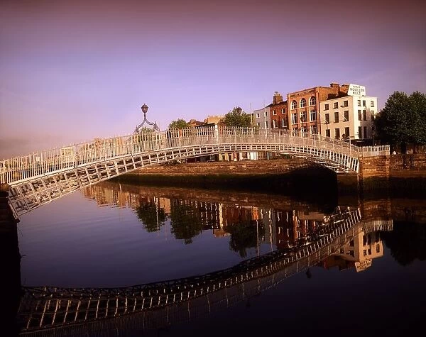 Ha penny Bridge, River Liffey, Dublin, Ireland; Bridge Reflected In River Against Cityscape