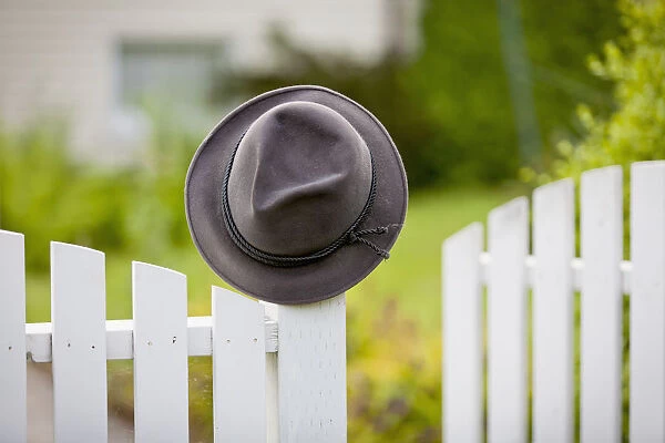 A Hat Hanging On The Post Of A White Picket Fence; Vancouver, British Columbia, Canada