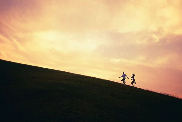 Hawaii, Couple Running Along A Hill At Sunset
