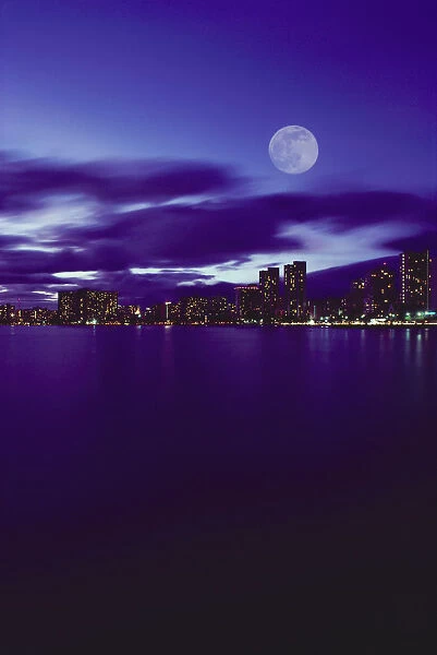 Hawaii, Oahu, Waikiki City Lights With Large Full Moon, Pale Purple Sky With Reflections On Water