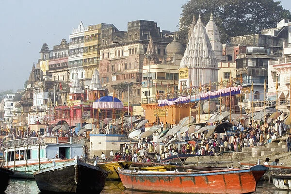 Hindu pilgrims immersed in the waters at the bathing ghats. Photograph taken while being rowed on the sacred but polluted River Ganges. The culture of Varanasi is closely associated with the River Ganges and the rivers religious importance. It is the re