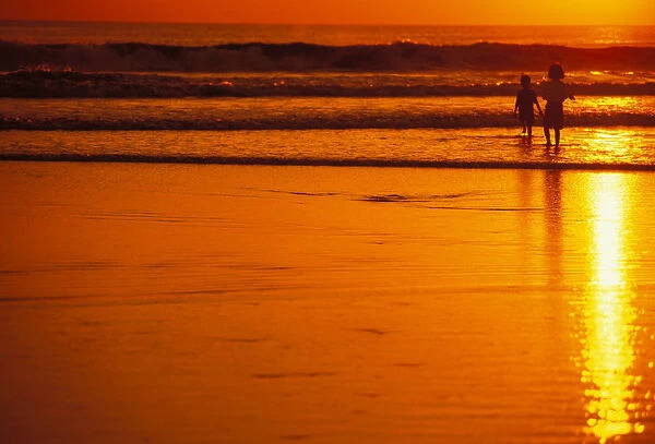 Indonesia, Bali, Kuta Beach At Sunset, Children Play In Shoreline, Orange Sky No Model Release