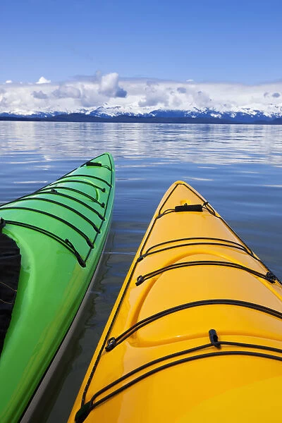 Kayakers enjoy a tranquil morning paddle in Lynn Canal, Alaska, near Juneau. Chilkat Mountains beyond
