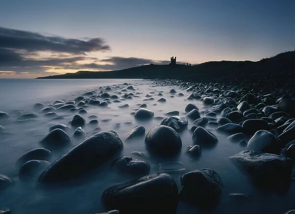 Large Boulders On Beach Near Dunstanburgh Castle At Dawn
