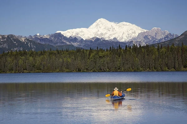 Man Paddling A Klepper Kayak On Byers Lake At Denali State Park. Mt. Mckinley Is Visible In The Background. August. Summer In The Interio Of Alaska