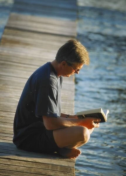 Man Reading His Book By The Waters Edge