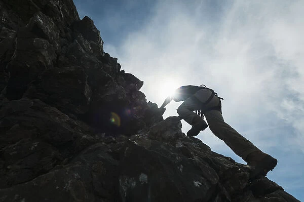Man Scrambling Up Ridge In The Black Cuillin; Isle Of Skye, Scotland
