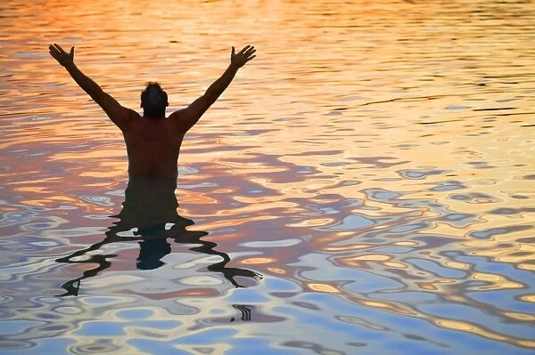 Man In Water Lifting Hands Towards Heaven