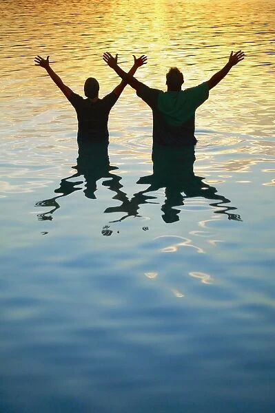 Two Men In Water Raising Hands