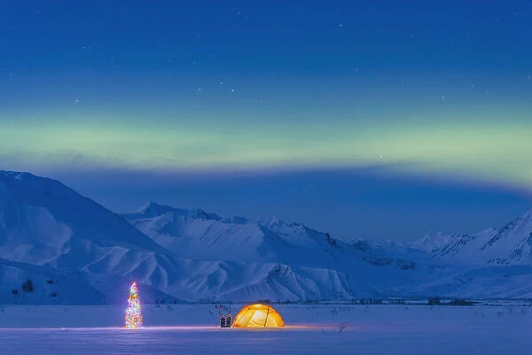 Northern Lights Glow In The Sky Above A Backpacking Tent And Lit Christmas Tree At Twilight Alaska Range In The Distance In Winter Isabel Pass Richardson Highway Interior Alaska; Anchorage Alaska United States Of America