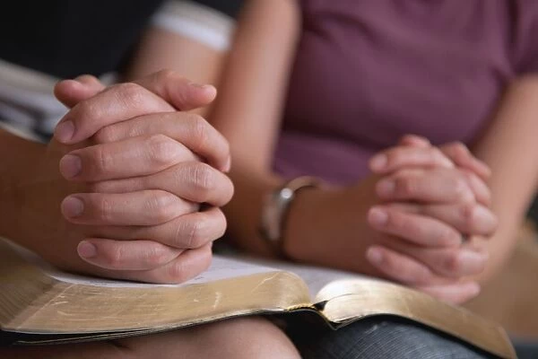 Praying Hands Of A Couple Reading The Bible Together