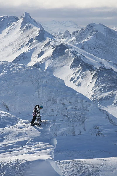 Professional Snowboarder Looking Over The Ledge At Extreme Terrain, Ushuaia, Patagonia, Argentina, South America