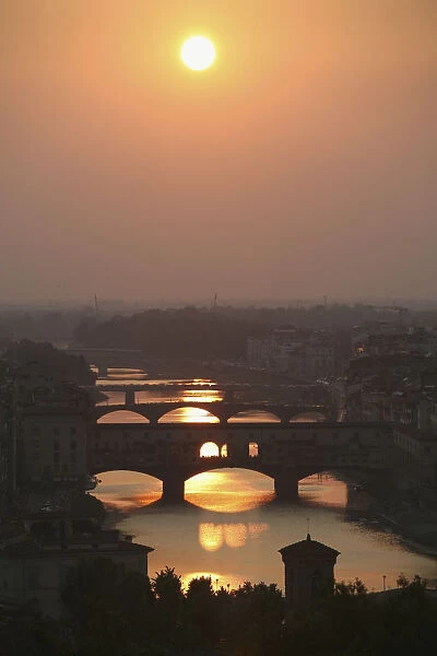 River Arno and famous bridge Ponte Vecchio, the oldest in Florence at sunset. Photo from hillside at large square Piazzale Michelangelo overlooking Firenze  /  Florence city in Tuscany. Italy. June
