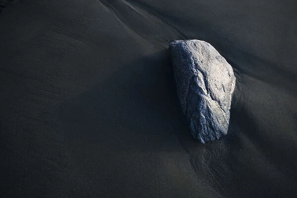 A Rock Sits On The Dark, Wet Sand; Alaska, United States Of America