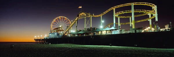 Rollercoaster And Ferris Wheel At Dusk On The Santa Monica Pier