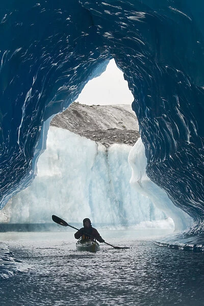 Sea Kayaker Paddles Through An Ice Cave Amongst Giant Icebergs Near Bear Glacier In Resurrection Bay Near Seward, Alaska