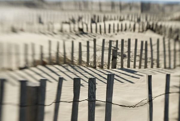 Slats Of Wooden Fence Throwing Shadows On Beach