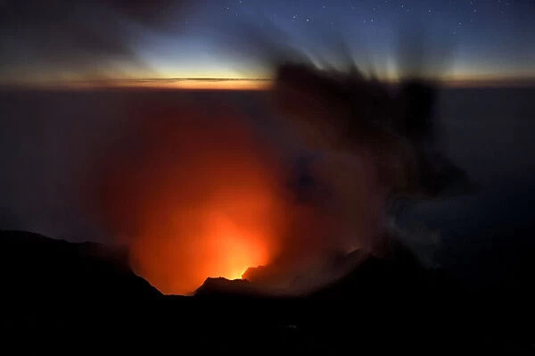 Smoke and ash rise up out of a volcano crater and into the evening sky