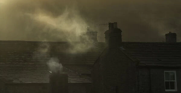 Smoke From Chimneys On A Rooftop Floats Into The Air; Reeth, Yorkshire, England