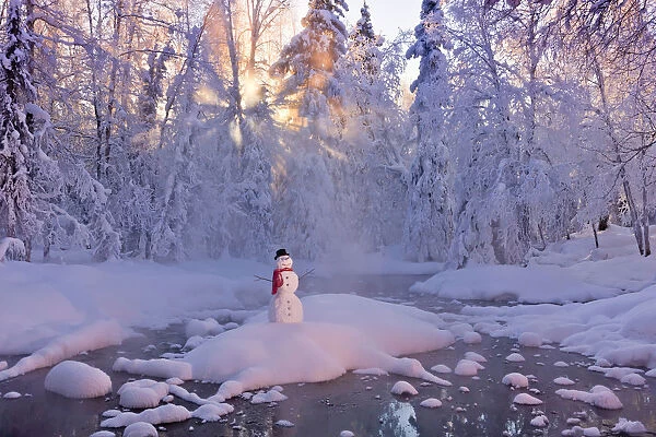Snowman Standing On A Small Island In The Middle Of A Stream With Sunrays Shining Through Fog And Hoar Frosted Trees In The Background, Russian Jack Springs Park, Anchorage, Southcentral Alaska, Winter. Digitally Enhanced