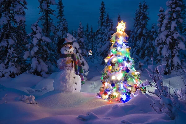 Snowman Stands In A Snowcovered Spruce Forest Next To A Decorated Christmas Tree In Wintertime