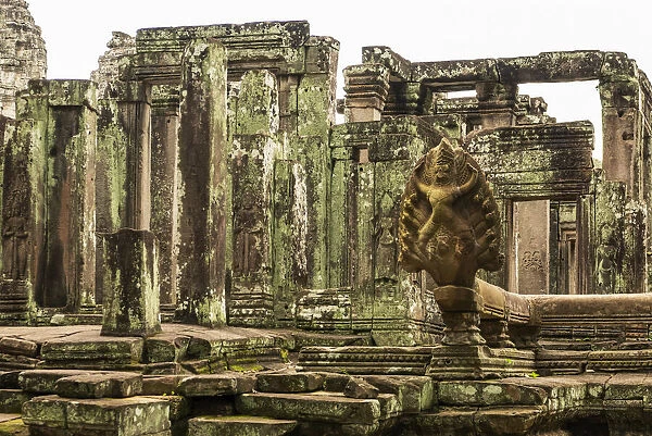 Statue in foreground of ruined Bayon temple, Angkor Wat, Cambodia