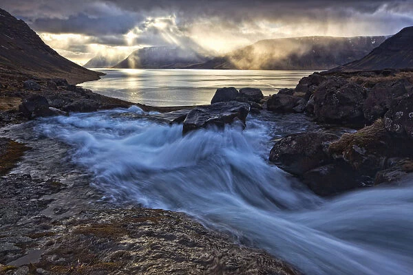 A Stormy Sky Breaks Above The Arnarfjorour Fjord At Sunset As Waterfall Dynjandi Flows Into It; Iceland